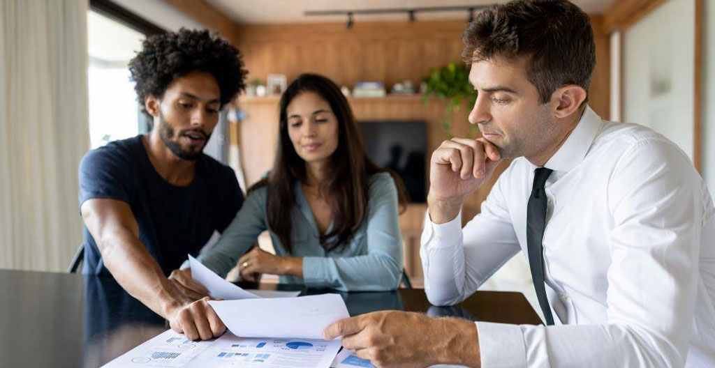 Conseiller bancaire travaillant sur une simulation de prêt relais immobilier dans une agence bancaire moderne avec écrans et documentation